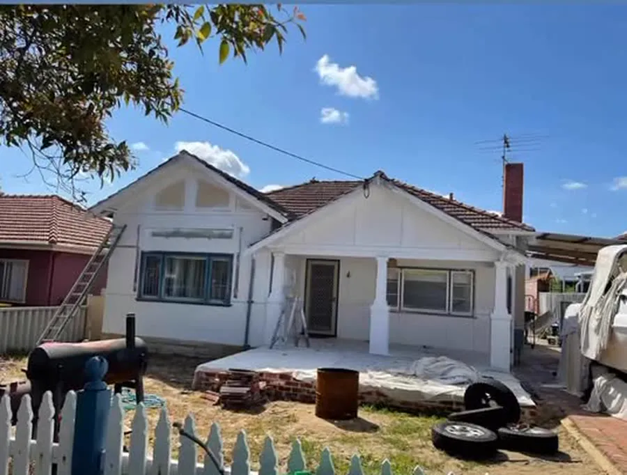 A character bungalow part-way through an exterior repaint, ladder and drop sheets in place